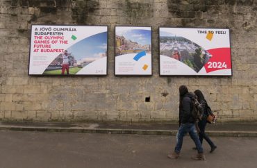 Passers by read an Olympic bid poster at the Citadella in Budapest Hungary February 20, 2017 (GamesBids Photo)